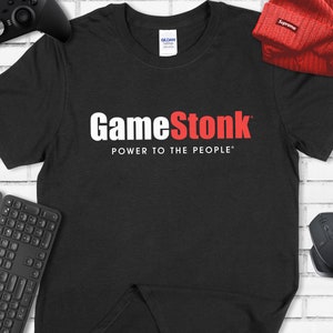 Könnte beinhalten: Schwarzes T-Shirt mit weißem Text, der "GameStonk" und "POWER TO THE PEOPLE" lautet. Das Wort "Stonk" ist rot.