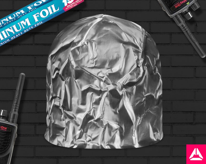 May include: A silver aluminum foil hat, crumpled and folded, with a black brick wall background.