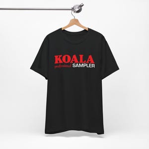 Puede incluir: Camiseta negra con el texto "KOALA professional SAMPLER" en letras rojas y blancas.