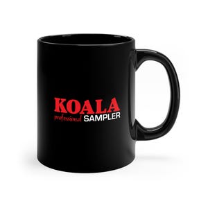 Puede incluir: Taza de café de cerámica negra con un logotipo rojo "KOALA professional SAMPLER".