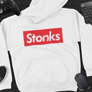Puede incluir: Sudadera con capucha blanca con una caja roja que dice "stonks" en letras blancas.