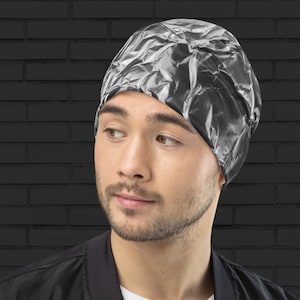 May include: A person wearing a silver foil beanie hat. The hat is made of crumpled foil and has a unique, textured look.