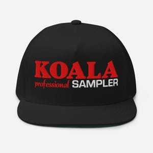 Pode incluir: Boné de beisebol preto de aba reta com a palavra "KOALA" bordada em letras vermelhas. Abaixo, o texto "professional SAMPLER" em branco. A parte inferior da viseira é verde.