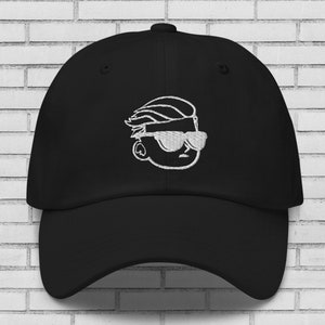 May include: A black baseball cap with a white embroidered design of a cartoon character wearing sunglasses.
