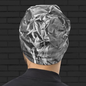 May include: A silver beanie with a crinkled, textured design. The beanie is made of a soft, stretchy material and is perfect for keeping your head warm in the winter.