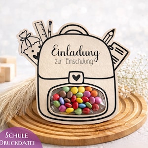 Puede incluir: Una tarjeta de invitación en forma de mochila de color claro con el texto "Einladung zur Einschulung". La tarjeta presenta una ventana transparente llena de caramelos de colores. También son visibles ilustraciones escolares y el texto "SCHULE Druckdatei".