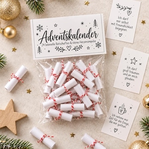 May include: A clear plastic bag containing 24 small white paper scrolls tied with red and white twine. The header card reads Adventskalender 24 liebevolle Botschaften & kleine Herzensimpulse. Three separate white cards with German text are included.