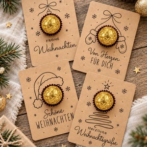 Könnte beinhalten: Vier rechteckige Karten aus Kraftpapier, jede mit einer goldfolierten Schokoladenkugel. Die Karten zeigen schwarze Strichzeichnungen von Weihnachtsschmuck, Fäustlingen, einer Weihnachtsmütze und einem Baum sowie deutschen Text wie Frohe Weihnachten.