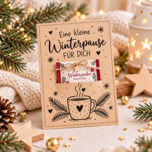Könnte beinhalten: Eine rechteckige Karte aus Kraftpapier mit dem schwarzen Aufdruck Eine kleine Winterpause FÜR DICH, einer Zeichnung einer dampfenden Tasse und einem Teebeutel mit der Aufschrift Winterzauber FRÜCHTETEE, befestigt mit einem Holzstern und Kordel.