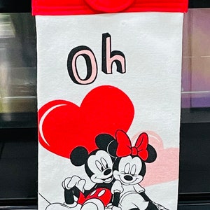 May include: White kitchen towel with a red heart, Mickey Mouse and Minnie Mouse, and the text "Oh Mickey". The towel has a red hanging loop with a white button.