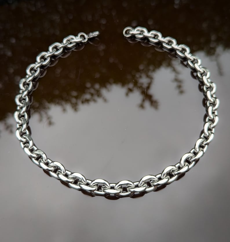 Puede incluir: Un collar de cadena de plata con un dise&ntilde;o de eslabones gruesos y redondeados.