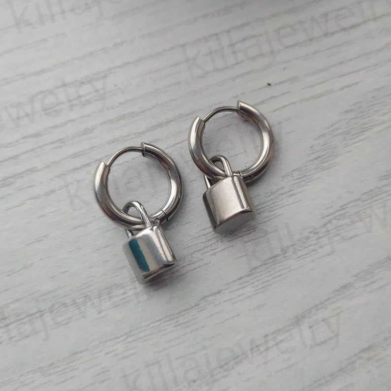 May include: A pair of silver hoop earrings with a small padlock charm hanging from each hoop.