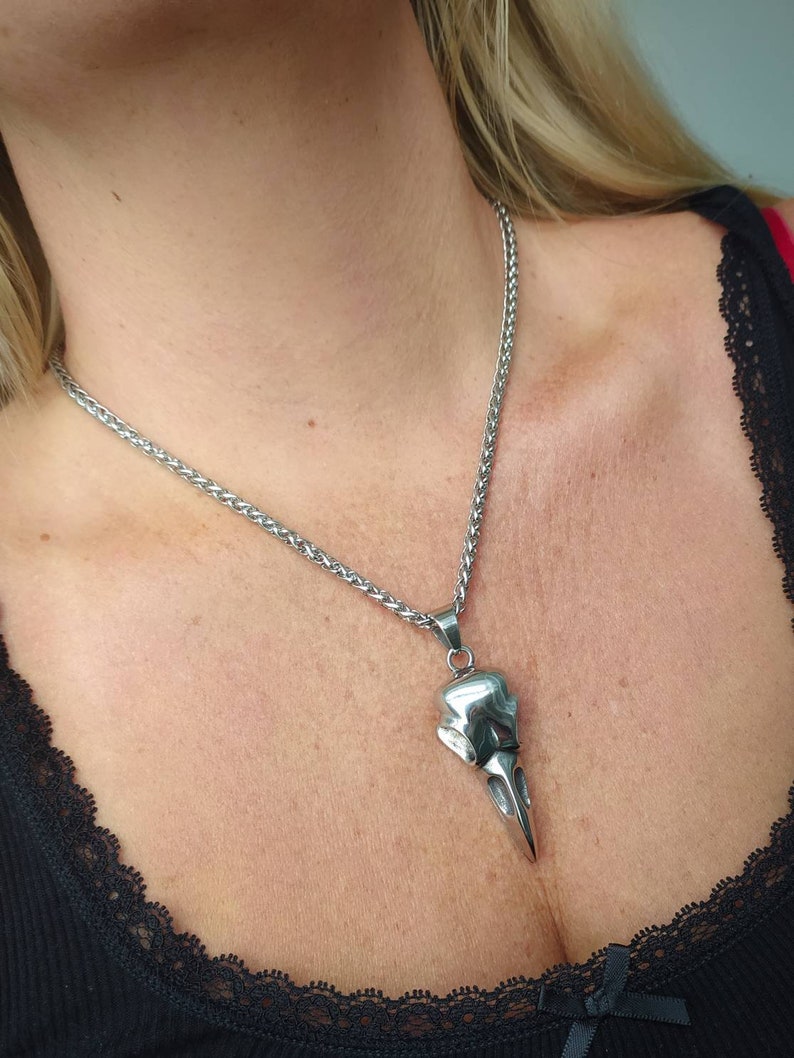 May include: A silver chain necklace with a detailed bird skull pendant. The pendant is a realistic depiction of a bird skull with a long beak.