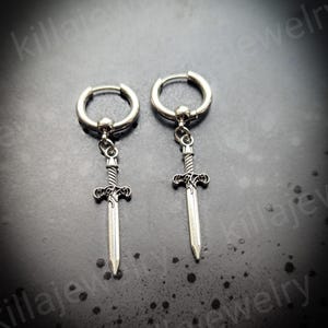 May include: A pair of silver hoop earrings with a sword pendant. The swords have a detailed design and are about 2 inches long.