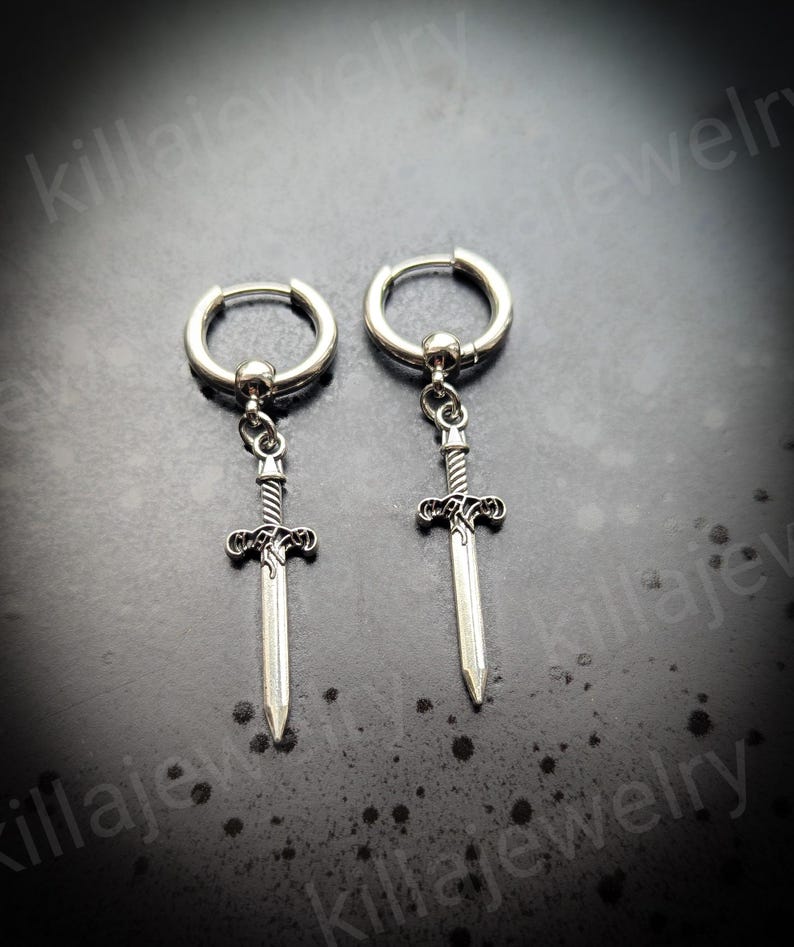 May include: A pair of silver hoop earrings with a sword pendant. The swords have a detailed design and are about 2 inches long.