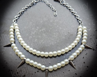 May include: A double-strand pearl necklace with silver spikes. The necklace has a silver clasp and is made of white pearls.