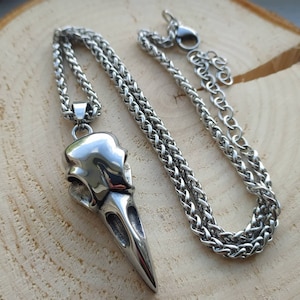 May include: A silver chain necklace with a detailed, three-dimensional bird skull pendant.