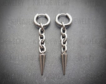 May include: A pair of silver hoop earrings with a dangling chain and a pointed tip. The earrings are made of stainless steel.