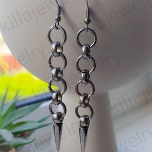 May include: A pair of silver earrings with a chain link design and a pointed spike at the bottom.