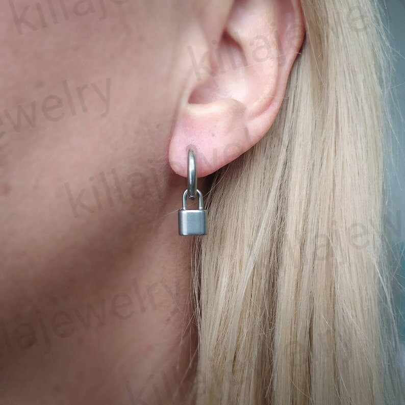 May include: A pair of silver padlock earrings. The earrings are hoop style with a small padlock charm hanging from each hoop.