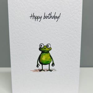 Tarjeta de cumpleaños con una rana alegre. Linda tarjeta de cumpleaños con una rana. Tarjeta de feliz cumpleaños con una rana.