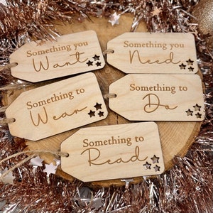 May include: Five wooden gift tags with a star design and the text "Something you Want", "Something you Need", "Something to Wear", "Something to Do", and "Something to Read".