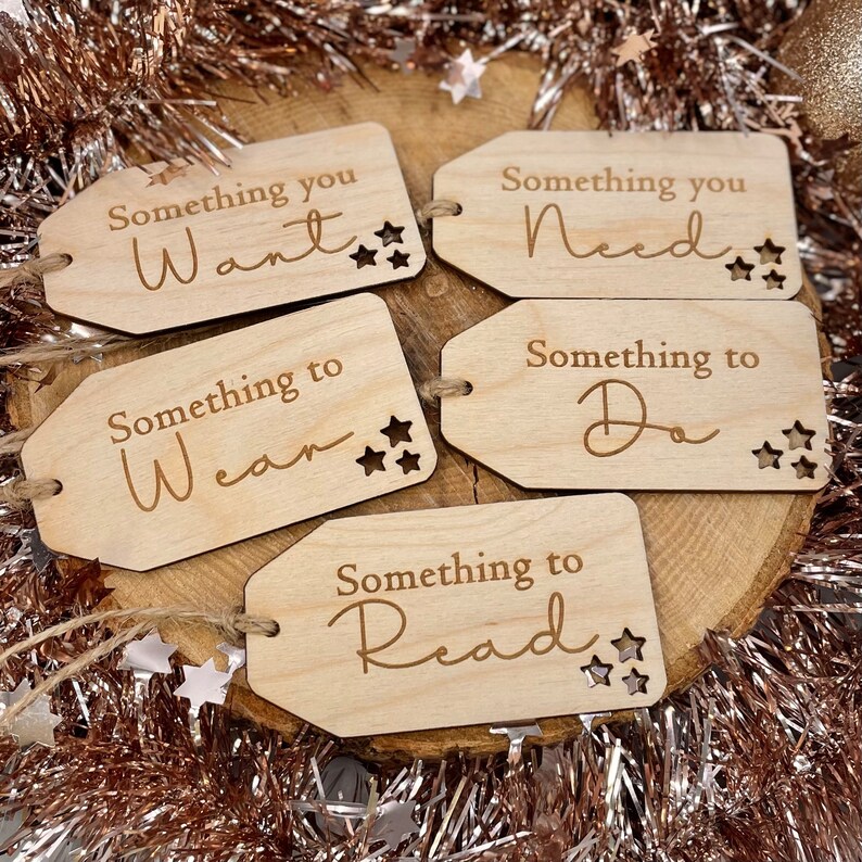 May include: Five wooden gift tags with a star design and the text "Something you Want", "Something you Need", "Something to Wear", "Something to Do", and "Something to Read".
