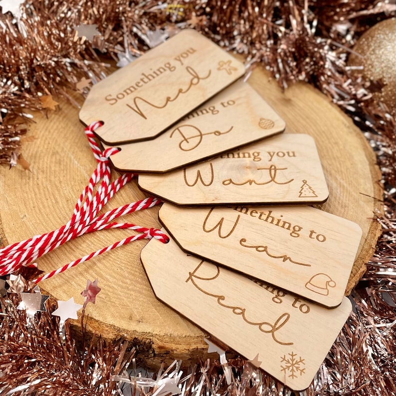 May include: Five wooden gift tags with red and white twine. The tags are rectangular and have the following text: Something you Need, Something to Do, Something you Want, Something to Wear, Something to Read.