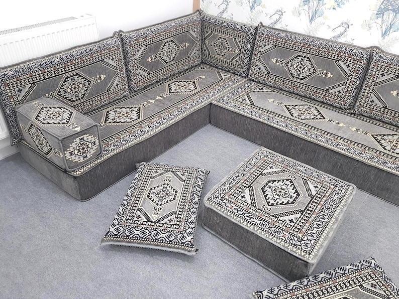 May include: A gray sectional sofa with matching ottomans and throw pillows. The sofa and ottomans have a geometric pattern in shades of gray, black, and white. The pillows have a similar design. The furniture is arranged in a corner configuration.