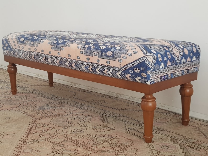 May include: A wooden bench with turned legs and a patterned fabric cushion. The fabric is a pink and blue geometric design.