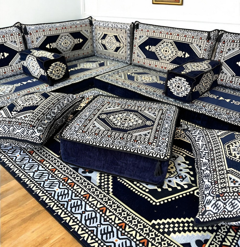May include: A set of blue and white patterned floor cushions and a matching rug. The cushions are arranged in a square shape, with a larger square cushion in the center. The rug has a geometric design and is made of a soft, plush material.