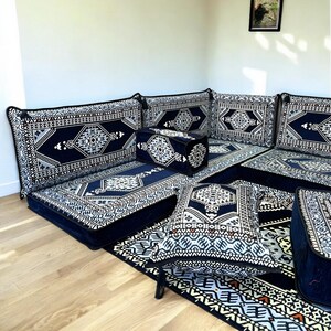 May include: A blue and white patterned floor seating set with a corner sofa, cushions, and a rug. The set is arranged in a traditional Moroccan style.