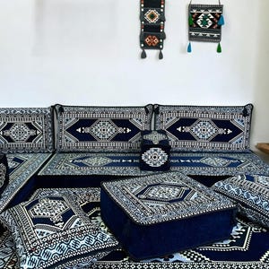 May include: A blue and white patterned floor cushion set with a variety of sizes and shapes. The cushions are arranged in a living room setting with a blue and white patterned rug.