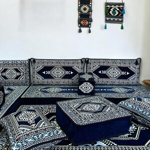 May include: A blue and white patterned floor cushion set with a variety of sizes and shapes. The cushions are arranged in a living room setting with a blue and white patterned rug.