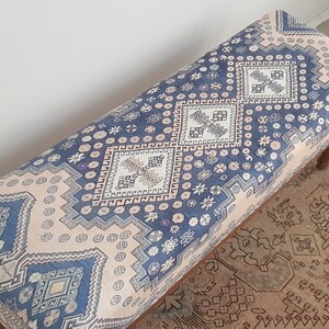 May include: A blue and pink patterned bench with a wooden frame. The bench has a geometric design with a repeating pattern of squares and diamonds.