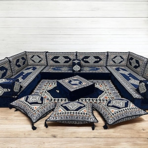 May include: A traditional Moroccan seating set with a blue and white patterned fabric. The set includes a large sofa, a smaller ottoman, and several throw pillows. The sofa is made up of multiple sections that can be arranged in different configurations.