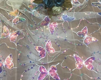 May include: White sheer fabric with pink and purple butterfly sequins. The fabric is decorated with small beads and sequins.