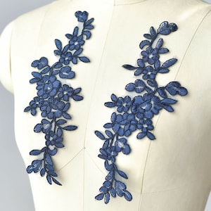 May include: Two navy blue floral lace appliques featuring delicate flower and leaf designs. These appliques are ideal for adding a touch of elegance to clothing, accessories, or home decor projects.