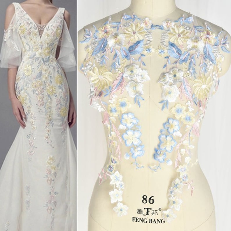 May include: Two pieces of delicate floral lace fabric in shades of blue, yellow, and pink. The lace is on a white background and has a delicate floral pattern. The lace is perfect for adding a touch of elegance to any project.
