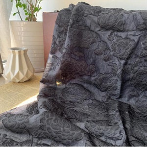 May include: Black fabric with an embossed floral pattern. The fabric has a soft, textured feel.