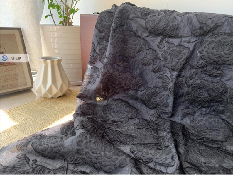 May include: Black fabric with an embossed floral pattern. The fabric has a soft, textured feel.