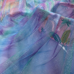 Könnte beinhalten: Ein hellblauer Tüllstoff mit schimmerndem Glitzer, der einen Regenbogen-Ombre-Effekt aufweist. Der Stoff ist weich und durchscheinend, perfekt für Bastelarbeiten und DIY-Projekte.