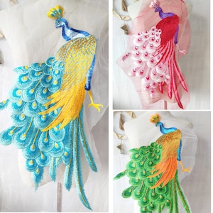 May include: Three embroidered peacock appliques in different colors. The peacock on the left has a blue and yellow tail, the middle peacock has a pink tail, and the peacock on the right has a green tail.