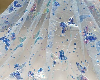 May include: White sheer fabric with iridescent blue butterfly sequins. The fabric is delicate and has a soft, flowing texture.