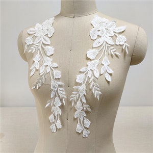 Könnte beinhalten: Zwei weiße florale Spitzenapplikationen mit Perlenbesatz, perfekt, um Brautkleidern, Braut-Accessoires oder anderen Bastelprojekten einen Hauch von Eleganz zu verleihen.