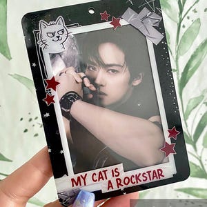 Könnte beinhalten: Schwarze rechteckige Fotokarte mit einem Foto einer Person. Die Karte hat einen weißen Rand, rote Sternakzente und den Text "MY CAT IS A ROCKSTAR". Eine Cartoon-Katze befindet sich in der oberen linken Ecke.
