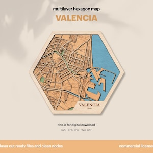 May include: A wooden, multi-layered hexagon map of Valencia, Spain. The map features a detailed laser-cut design with a light brown city layout, a blue water section, and the city name in a gold color. The text "VALENCIA" is displayed prominently.