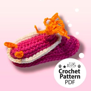 May include: A handmade crochet slipper in shades of pink and white, with orange accents. The slipper features a textured stitch pattern and a decorative orange element on top. The image includes the text "Crochet Pattern PDF".