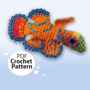 May include: Crochet pattern for a colorful fish with orange, blue, green, and red yarn. The pattern is available as a PDF download.