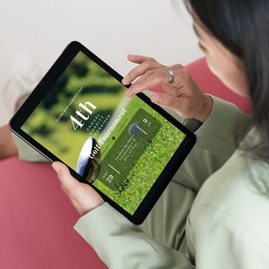 May include: A digital tablet displaying a flyer for the 4th Annual Charity Fundraiser Golf Tournament. The flyer is on a green background with a golf ball and the text "Come and support our 4th Annual Charity Fundraiser Golf Tournament" and "May 29, 9 AM".